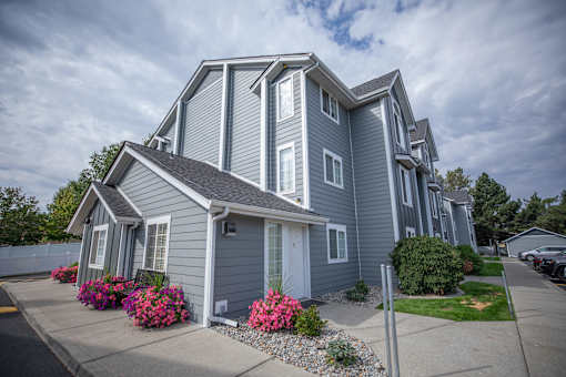 A grey house with a white door and windows at Morning Glory Circle Apartments, Spokane, WA