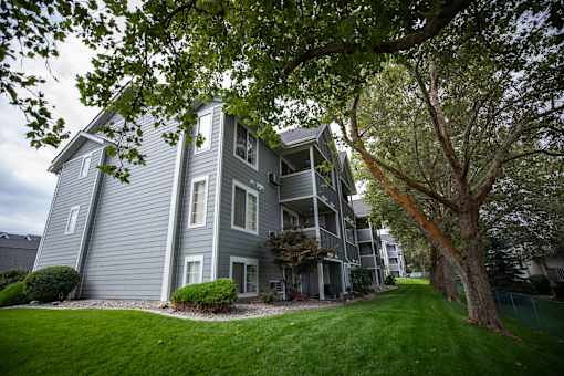 A grey apartment building with a tree at Morning Glory Circle Apartments, Washington, 99208