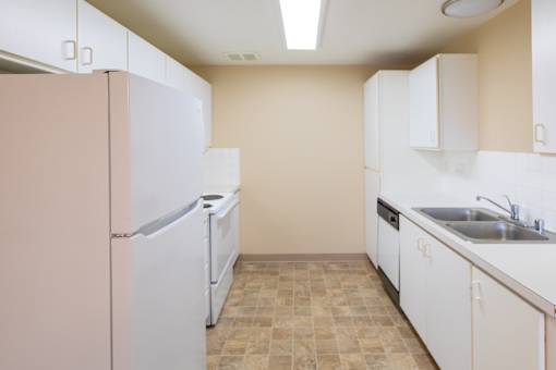 A kitchen with a pink refrigerator and white cabinets.