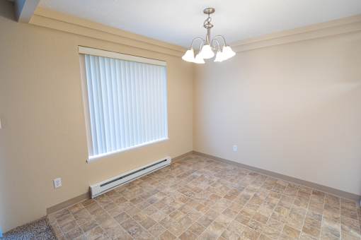 A room with a window, tiled floor, and a chandelier.