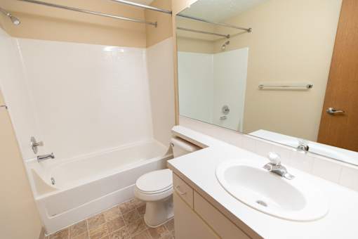 A white bathroom with a toilet, sink, and bathtub.