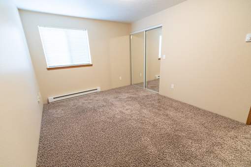 A room with a carpeted floor, a window, and a sliding glass door.