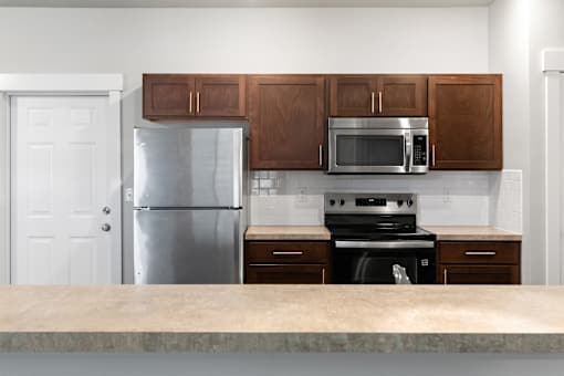 A kitchen with a refrigerator, microwave, oven, and cabinets.at The Brix Apartments, Washington