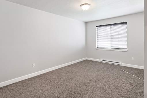 A room with a carpeted floor and a window with blinds.at The Brix Apartments, Spokane Valley, 99037
