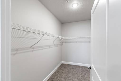 A white closet with a carpeted floor and a white door.at The Brix Apartments, Spokane Valley, Washington
