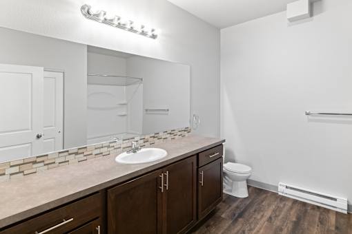 A bathroom with a white sink and brown cabinets.at The Brix Apartments, Washington