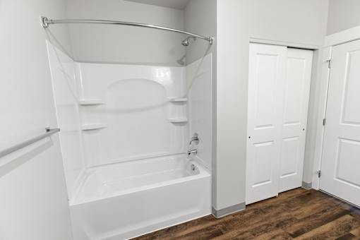 A white bathroom with a tub and a towel rack.at The Brix Apartments, Washington, 99037