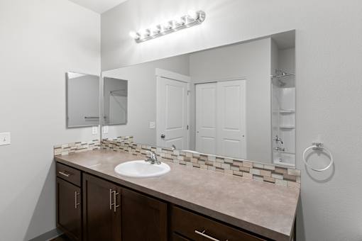 A bathroom with a sink, mirror, and cabinets.at The Brix Apartments, Spokane Valley, WA