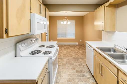 A kitchen with a white stove top oven and a white microwave above it at Graymayre Crossing Apartments, Spokane, WA, 99208