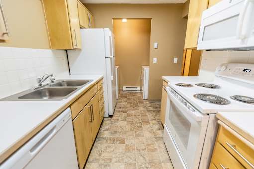 A kitchen with white appliances and wooden cabinets at Graymayre Crossing Apartments, WA, 99208