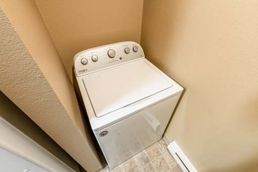 A white washing machine in a small room at Graymayre Crossing Apartments, Spokane, 99208