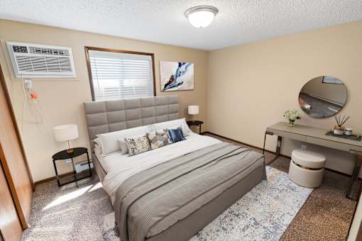 A bedroom with a bed, desk, and window.