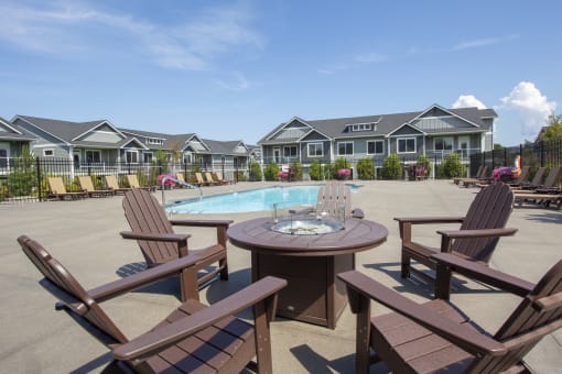 a patio with a table and chairs next to a pool with houses in the background at The Brix Apartments, Washington