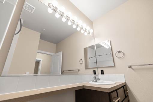 A bathroom with a sink, mirror, and lights.