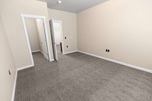 A room with carpeted floor and two open doors.