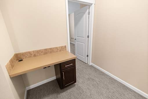 A corner desk with a drawer and a door in the background.