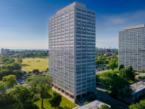 an aerial view of a tall skyscraper with trees in the foreground and a city in the