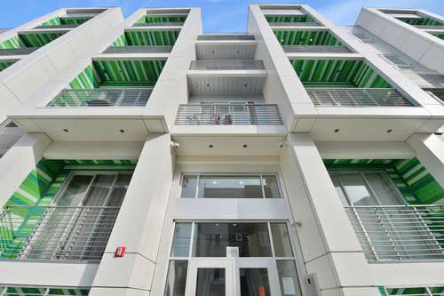 A modern white building with green stripes on the balconies.