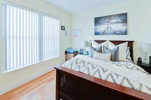 A bedroom with a large bed and a painting on the wall.