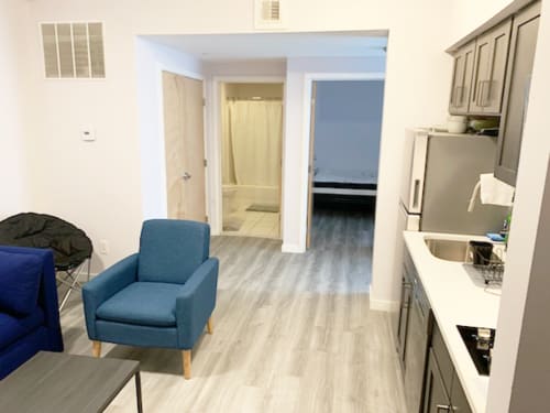 A blue chair sits in a kitchen with a sink and a window.