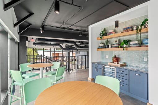 a community space with blue tables and chairs and a kitchen