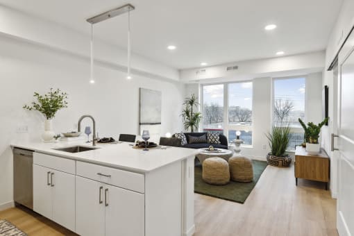 an open kitchen and living room with white cabinets and a large window
