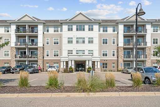 A large apartment complex with multiple balconies and cars parked in the lot.