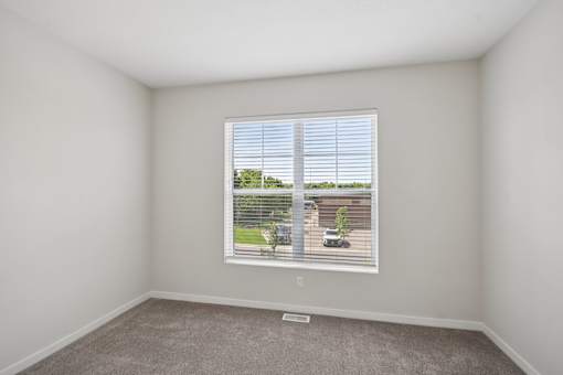 A room with a window showing a view of a fence and a tree.