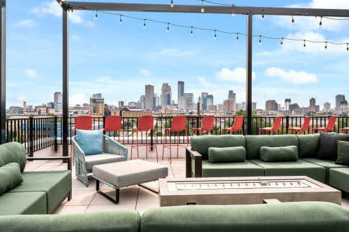 Rooftop deck with green couches and chairs and a view of the city