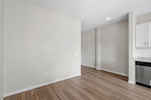 A kitchen with white cabinets and a wooden floor.