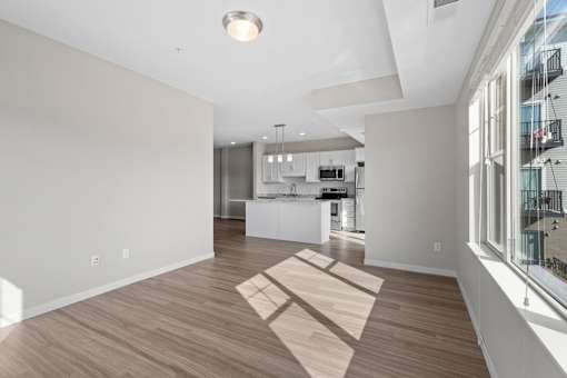A spacious kitchen and living room with wooden flooring and white walls.