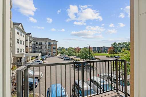 A balcony view of a parking lot with cars and buildings.