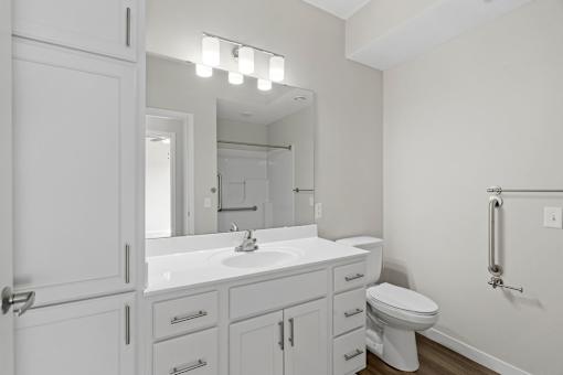 A white bathroom with a toilet, sink, and mirror.