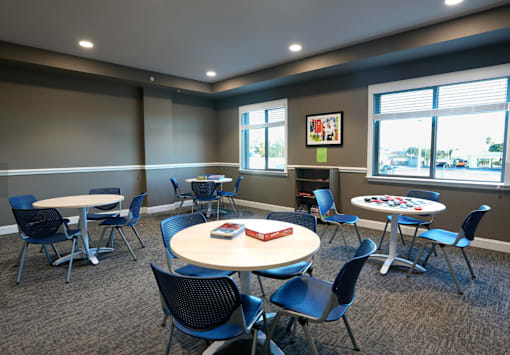 A room with tables and chairs and a window.
