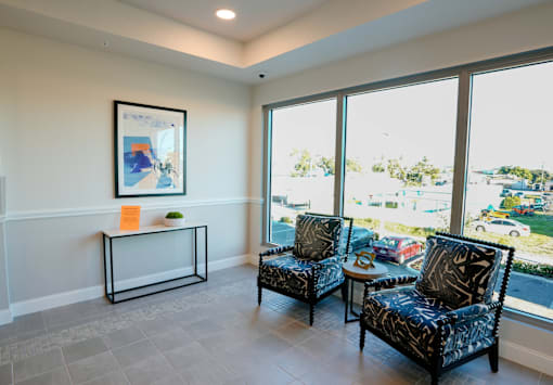 Two black patterned chairs are placed in a room with a large window.