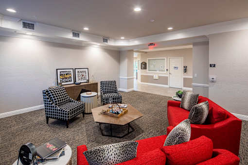 A living room with a red couch and a grey chair.