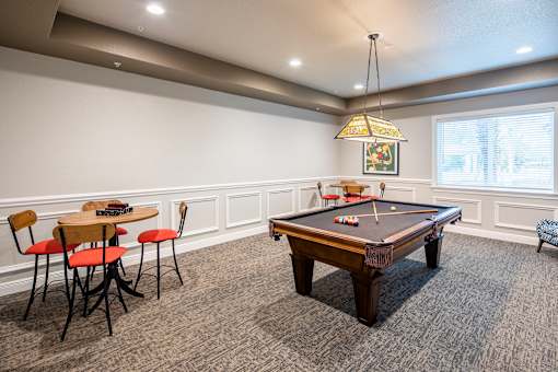 A pool table is in the middle of a room with chairs and a table.