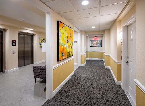 A hallway with a large painting on the wall and a bench on the floor.