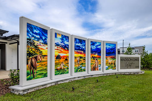 A row of four large paintings of horses in a field with the text "MADISON OAKS" on the right.