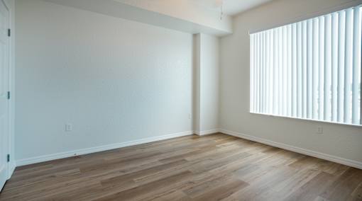 A room with wooden flooring and a window with blinds.
