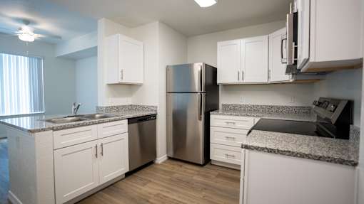 A kitchen with white cabinets and a granite countertop.