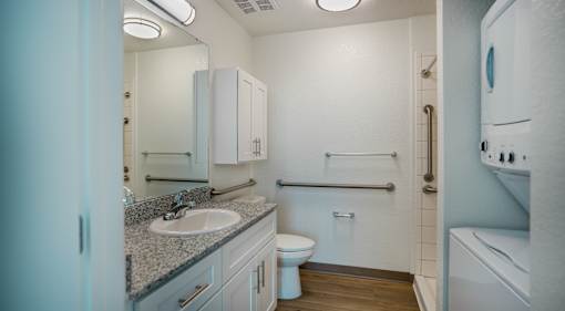 A bathroom with a toilet, sink, and mirror.