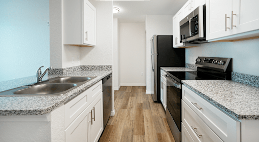 A kitchen with white cabinets and a black refrigerator.