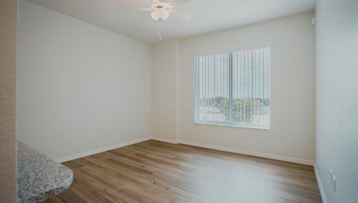 Empty room with a window and wooden floor.