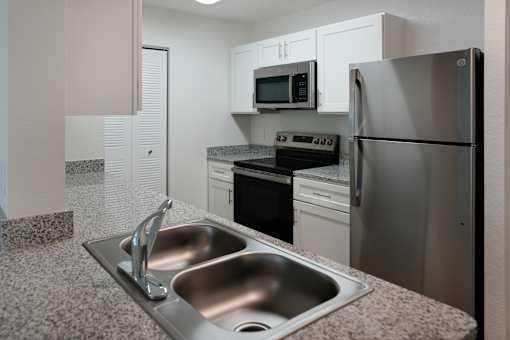 A modern kitchen with a stainless steel refrigerator, microwave, and oven.