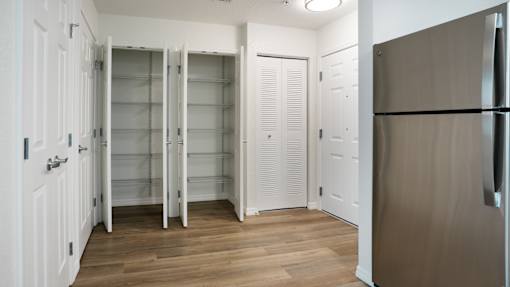 A kitchen with a refrigerator, cupboards and a pantry.