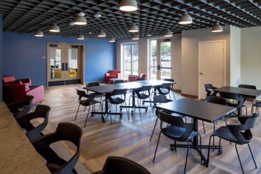 A room with tables and chairs and a ceiling with lights.