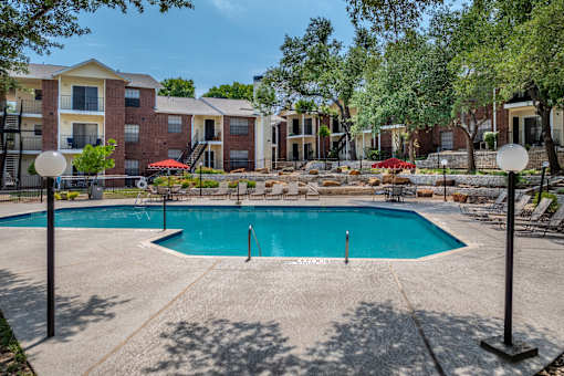 A swimming pool surrounded by apartment buildings and trees.