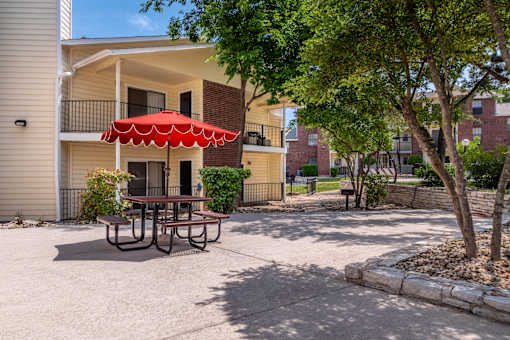 A red umbrella is on a table in the courtyard of a building.
