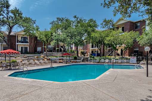 A swimming pool surrounded by trees and chairs.
